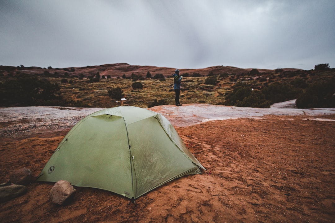 A tent pitched under overcast skies in a rugged outdoor setting