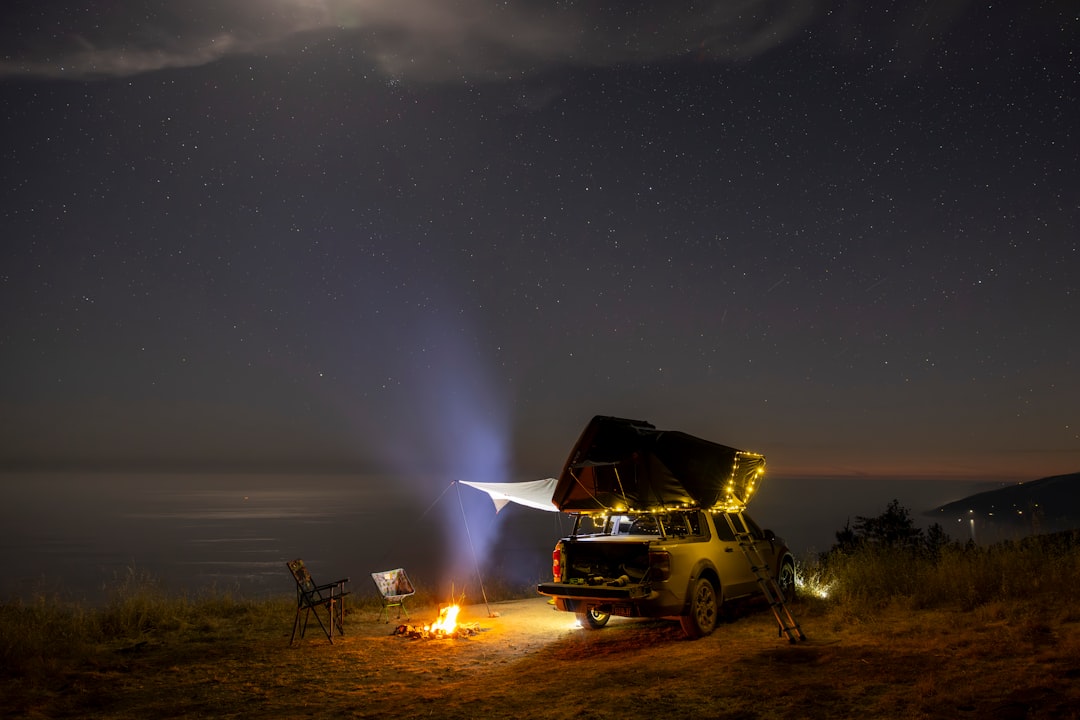 A vehicle with a rooftop tent parked outdoors under a clear starry night sky