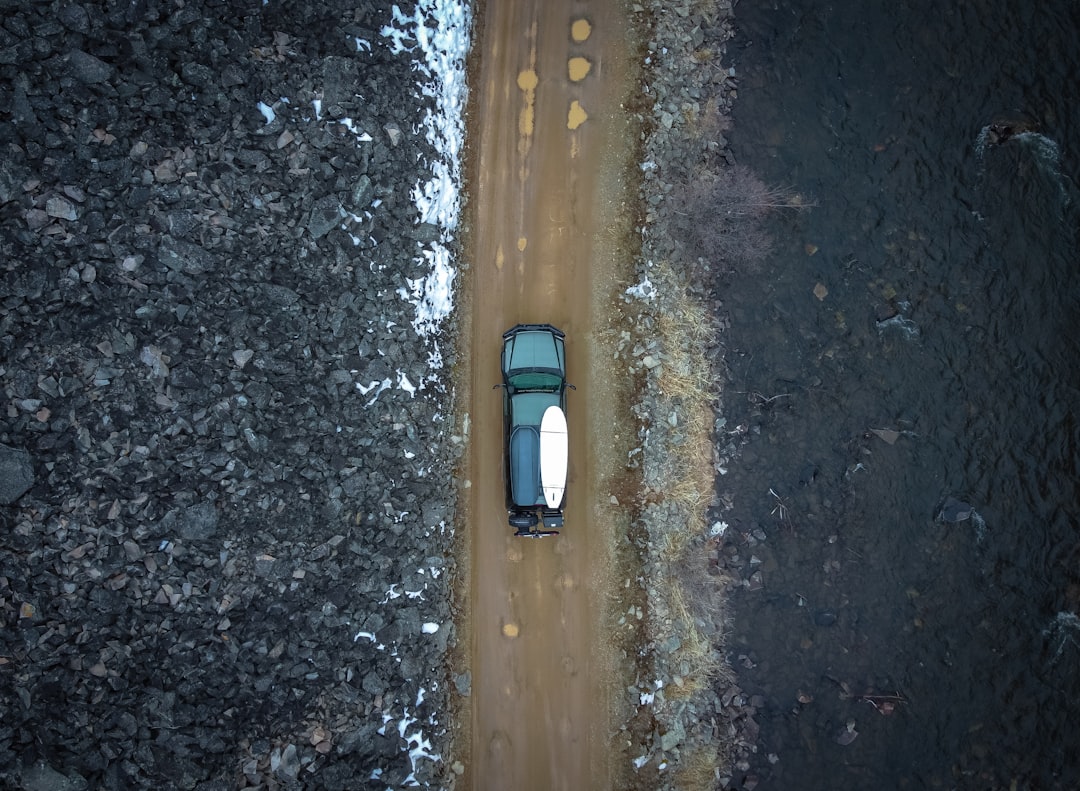 A 4x4 truck driving a rugged dirt trail through dense forest terrain