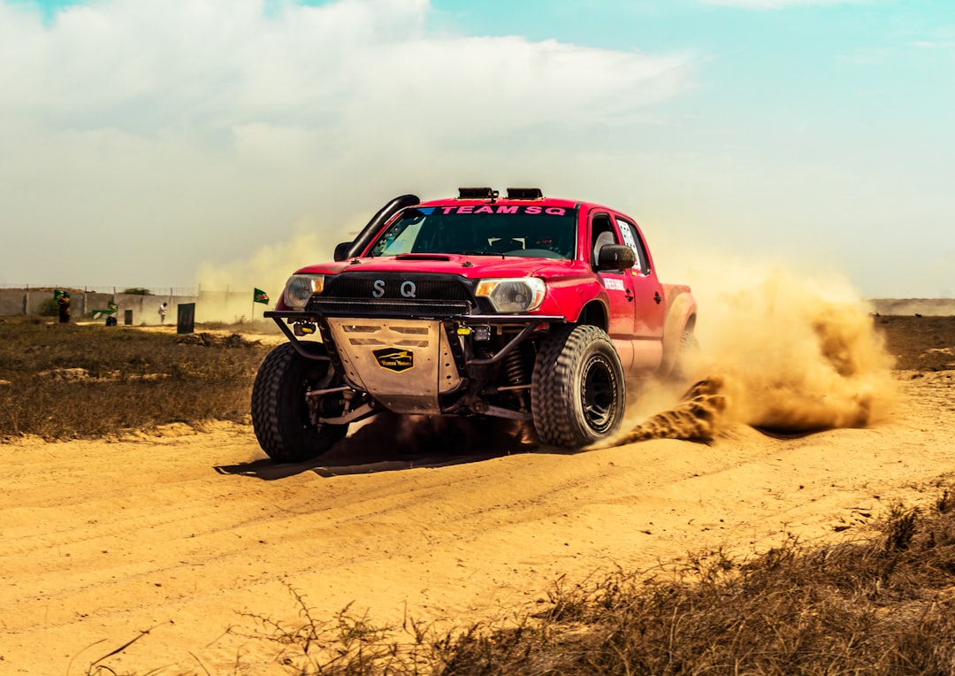 Red truck driving down a dirt road with off-road recovery equipment